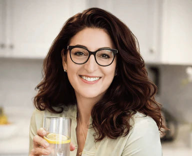 Woman holding a glass of water with a lemon in a kitchen setting
